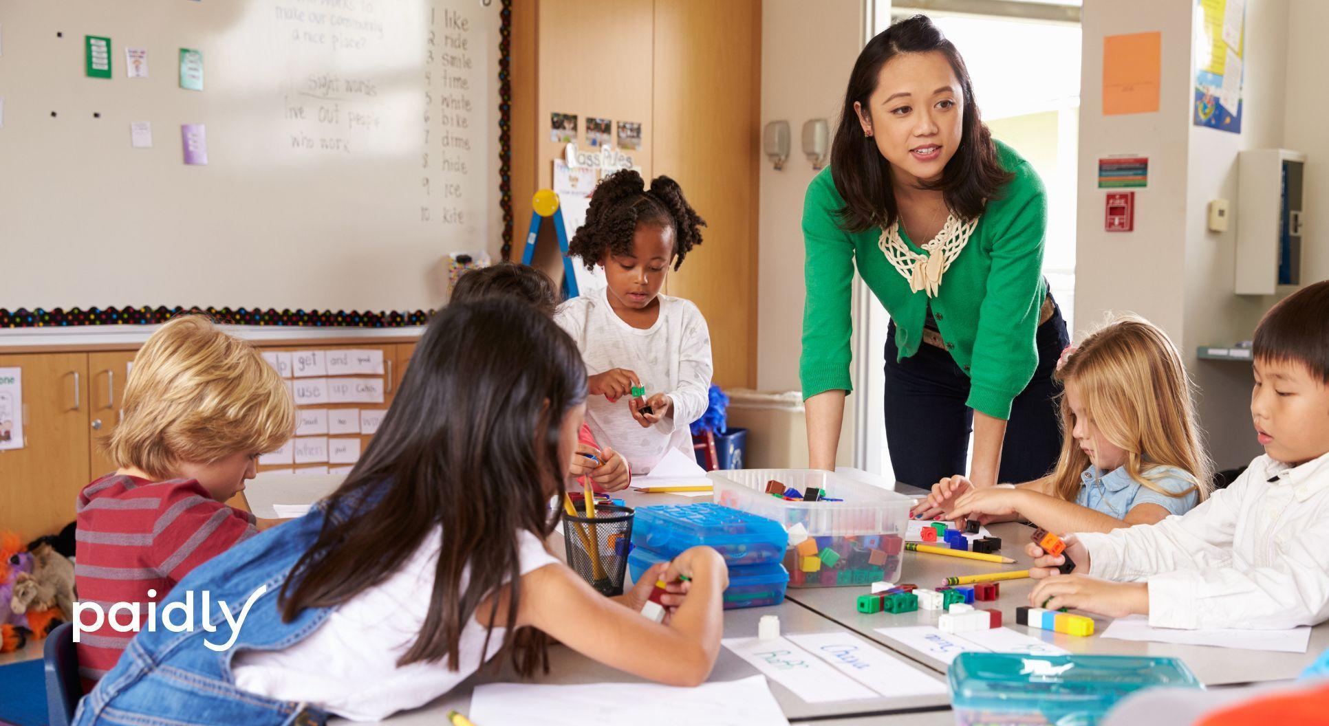 teacher leaning over a desk helping students