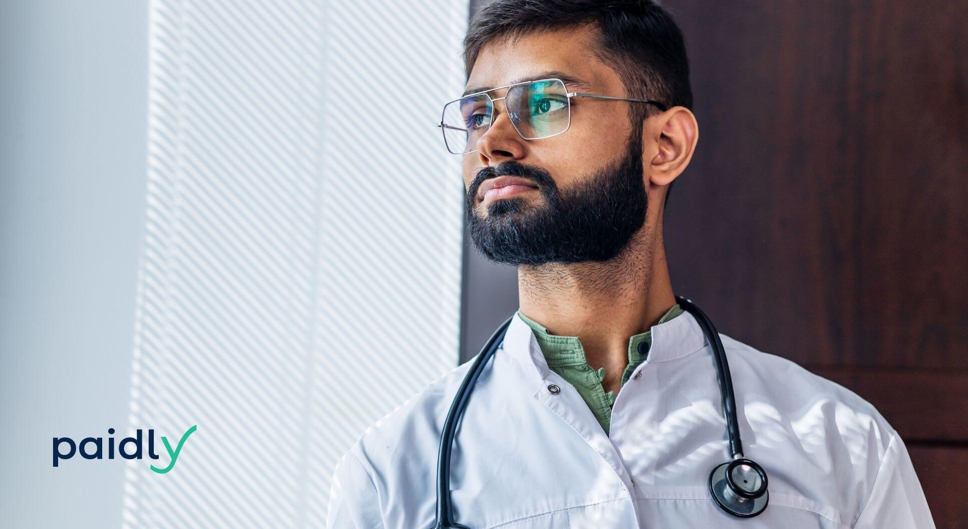 Portrait of a Male Indian Doctor wearing white coat in clinic office