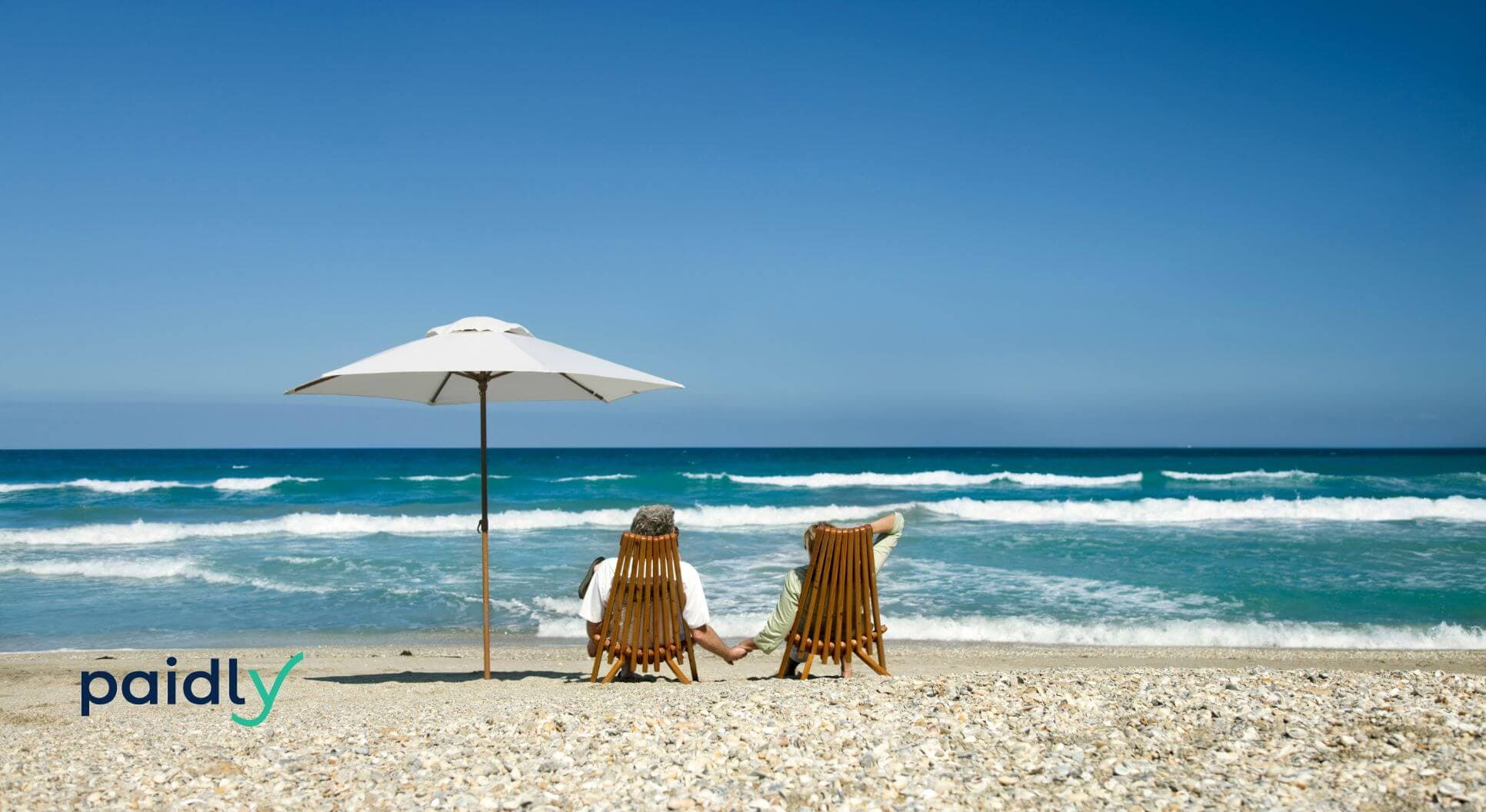 Two people on a beach holding hands looking at the water relaxed