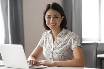 Ready to get started reducing student loan debt Person smiling at a laptop ready to get started reducing student loan debt