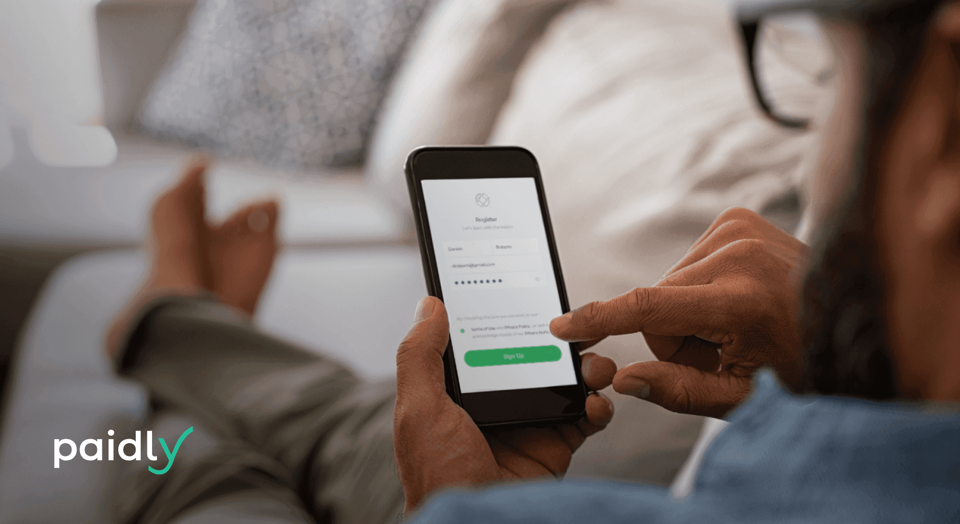 The benefits and pitfalls of student loan autopay Man sitting on couch looking at loans on phone