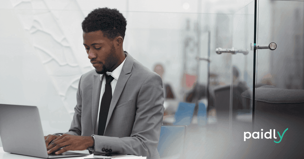 Preparing for the Talent Storm: Student Loan Benefits for Recruitment & Retention Man using a laptop in office with Paidly logo